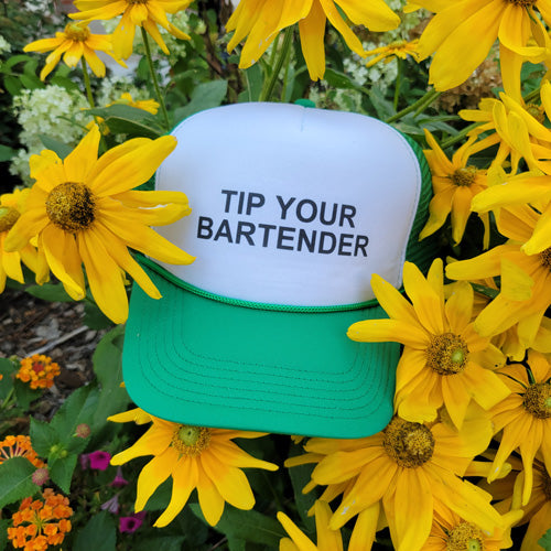 Green trucker hat with text "tip your bartender on front of hat with sunflowers in background